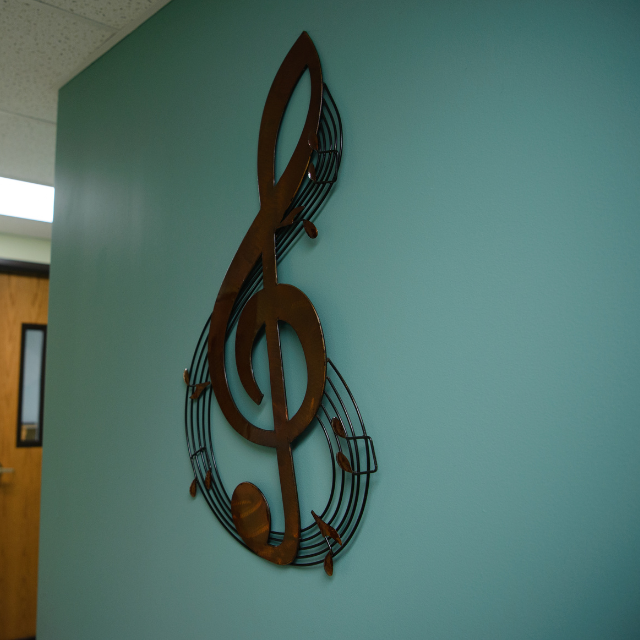 green wall with large metal treble clef mounted on it